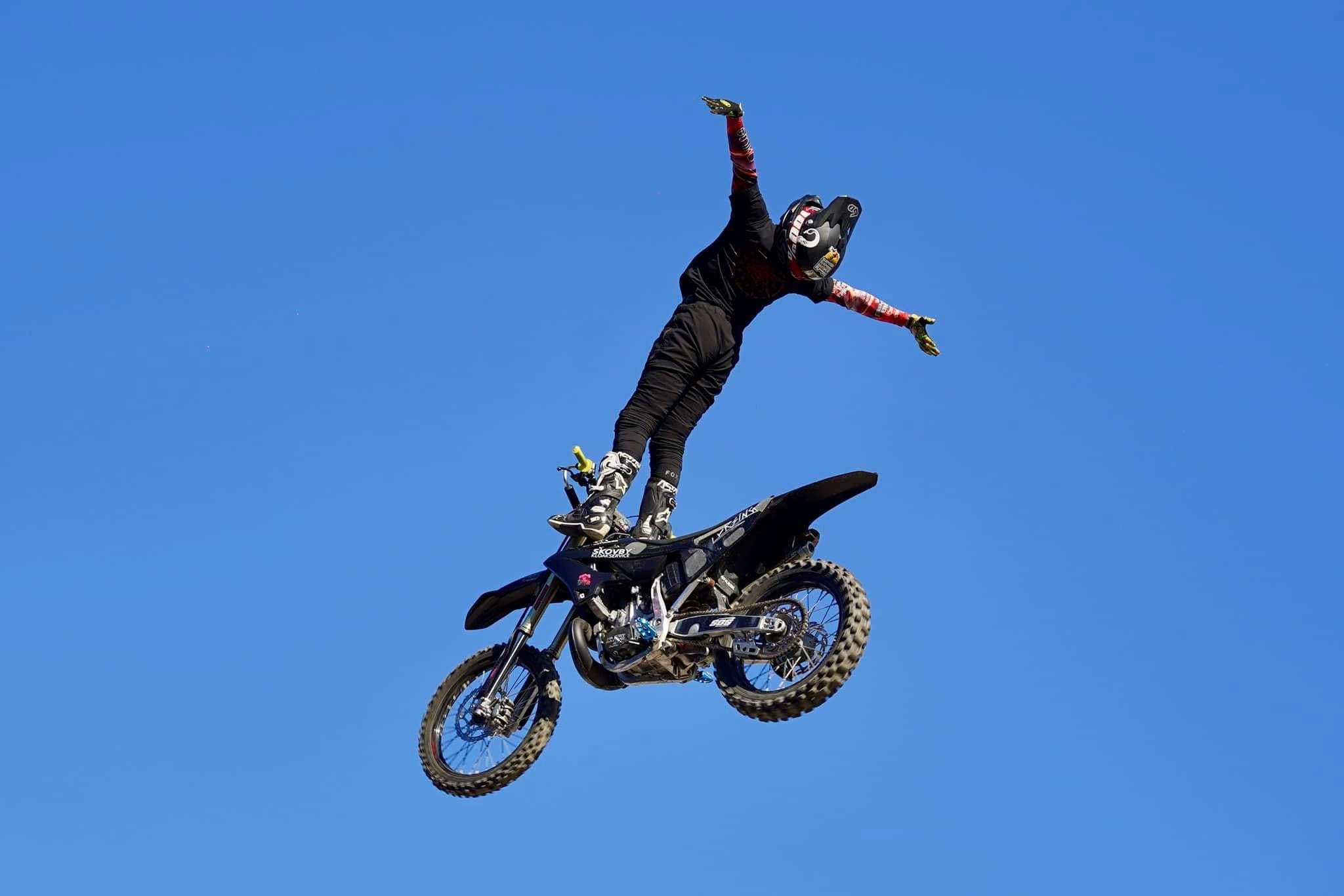 Alex Porsing standing on bike mid-air stunt